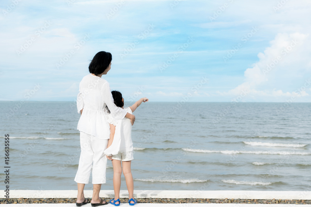 海边暑假快乐的亚洲家庭母女。母女站着