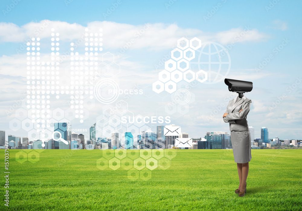 Camera headed woman standing on green grass against modern cityscape