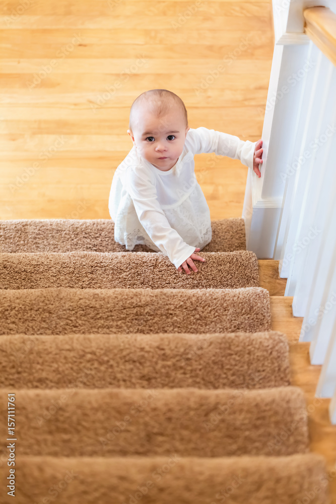 Happy toddler girl climbing the stairs in her house