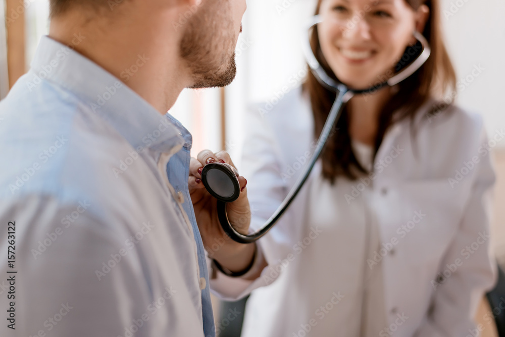 Female doctor checking heart beat of patient.