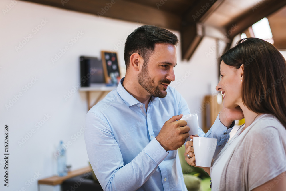 Closeup of beautiful young couple looking at each other and smiling while enjoying coffee in cafe to