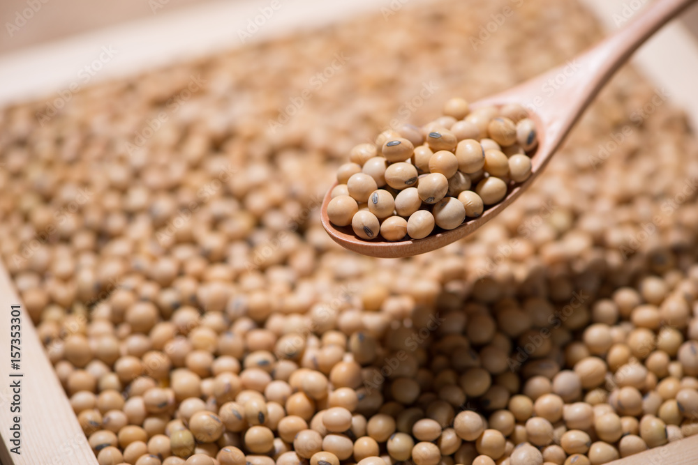 Soya beans in spoon on wooden table.