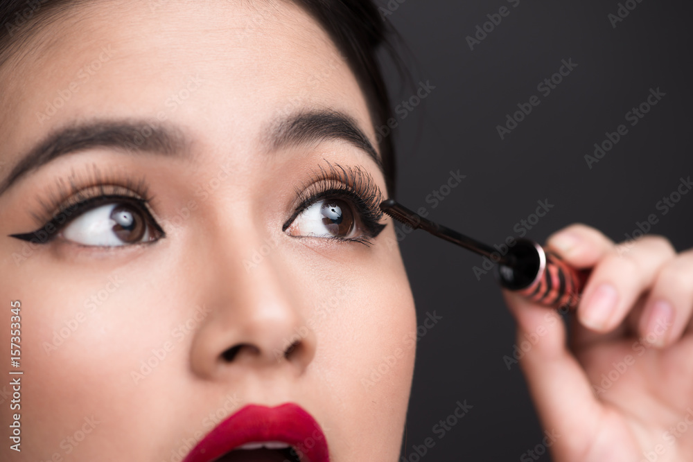 Make-up and cosmetics concept. Asian woman doing her makeup eyelashes black mascara.