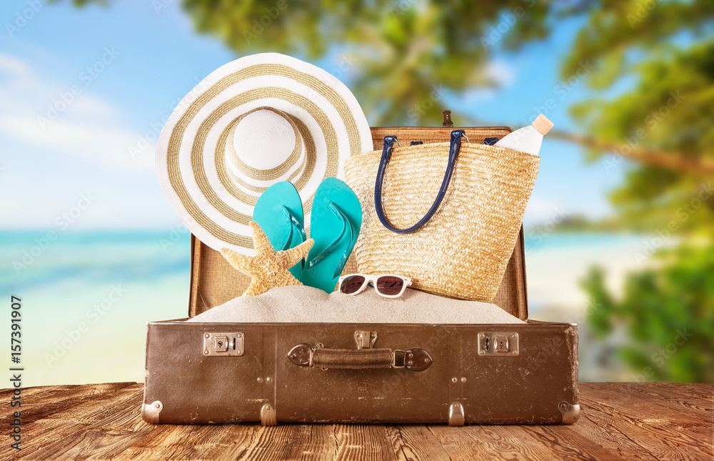 Retro luggage with summer beach holiday accessories placed on wooden planks