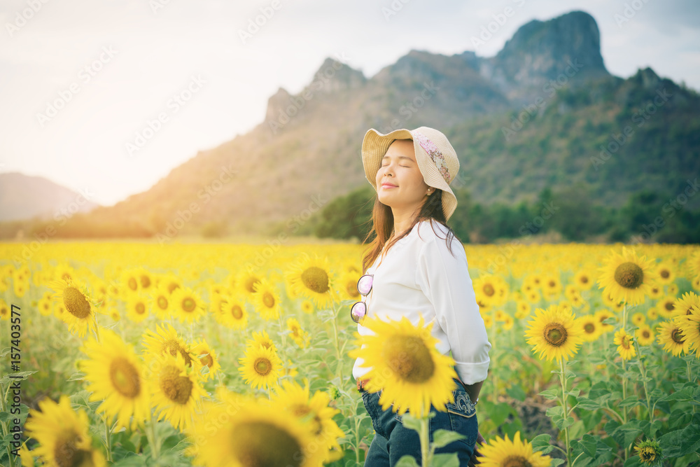 Happy woman in sunflower field smiling with happiness