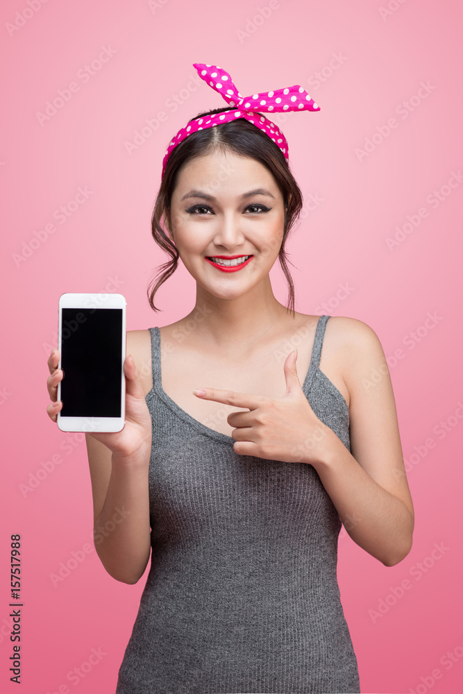 Beautiful young asian woman with pin-up make-up and hairstyle over pink background with mobile phone