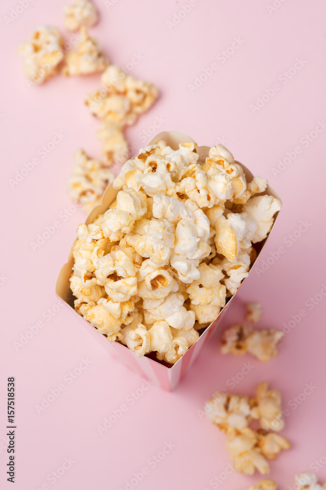 Popcorn in red and white cardboard box on the pink background.