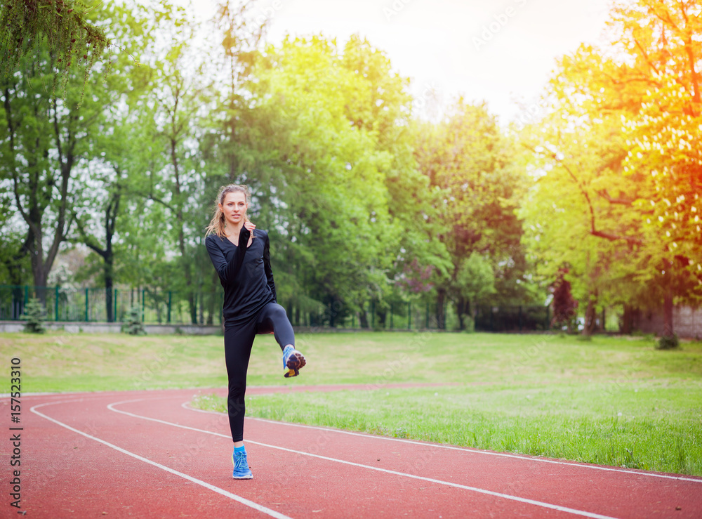 Athletic woman stretching on running track before training, healthy lifestyle