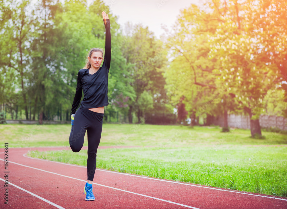 Athletic woman stretching on running track before training, healthy lifestyle