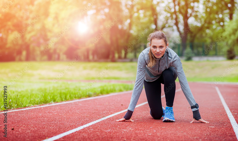 Athletic woman on running track getting ready to start