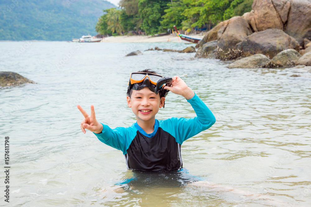 年轻的亚洲男孩戴着口罩在海水中浮潜