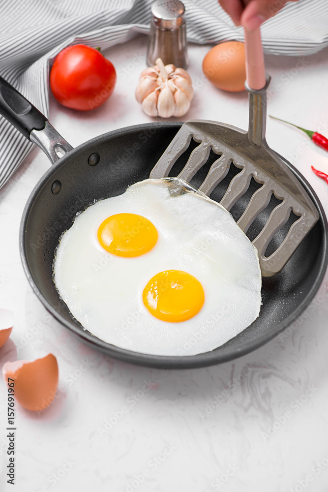 Fried eggs in a frying pan with cherry tomatoes and bread for breakfast