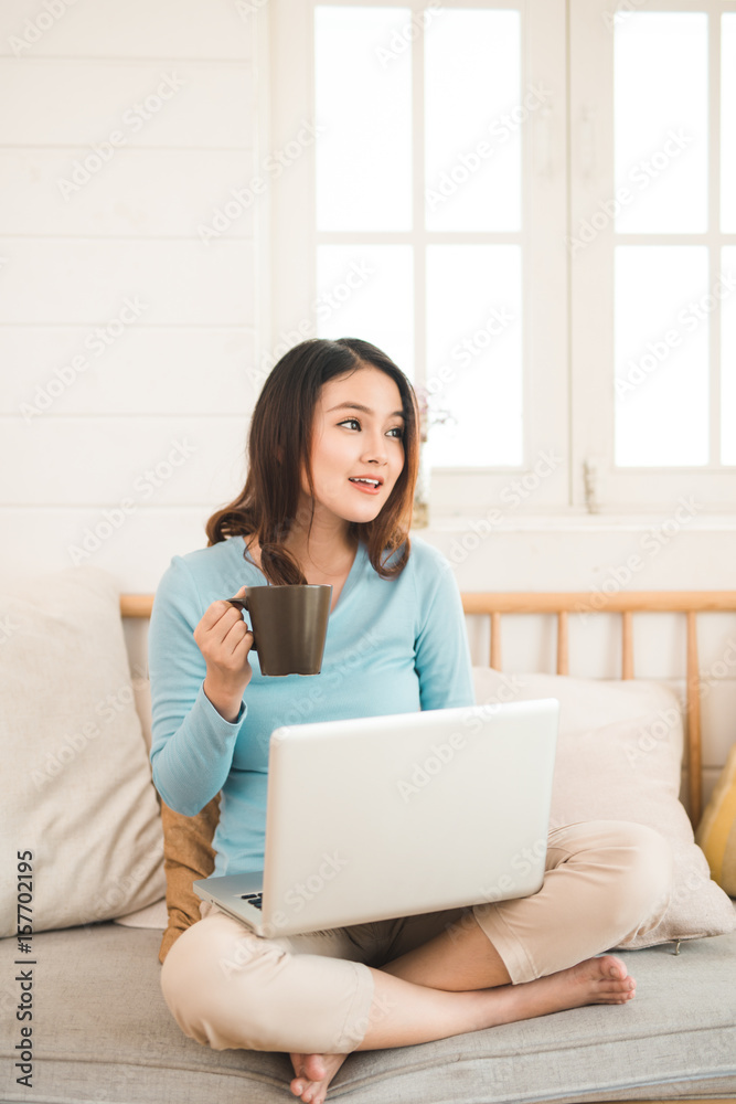 Happy casual beautiful asian young woman working on a laptop at home.