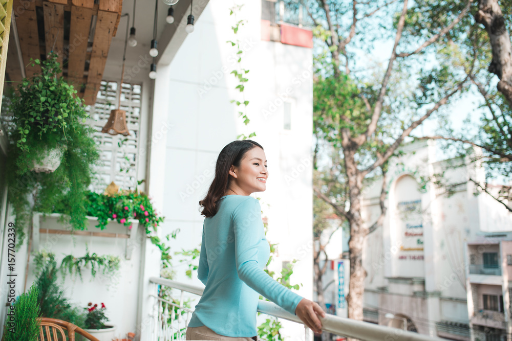 Beautiful asian girl enjoying the freshness on balcony