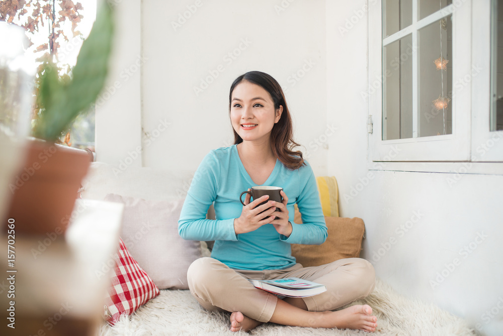 Portrait of young asian woman reading book at home