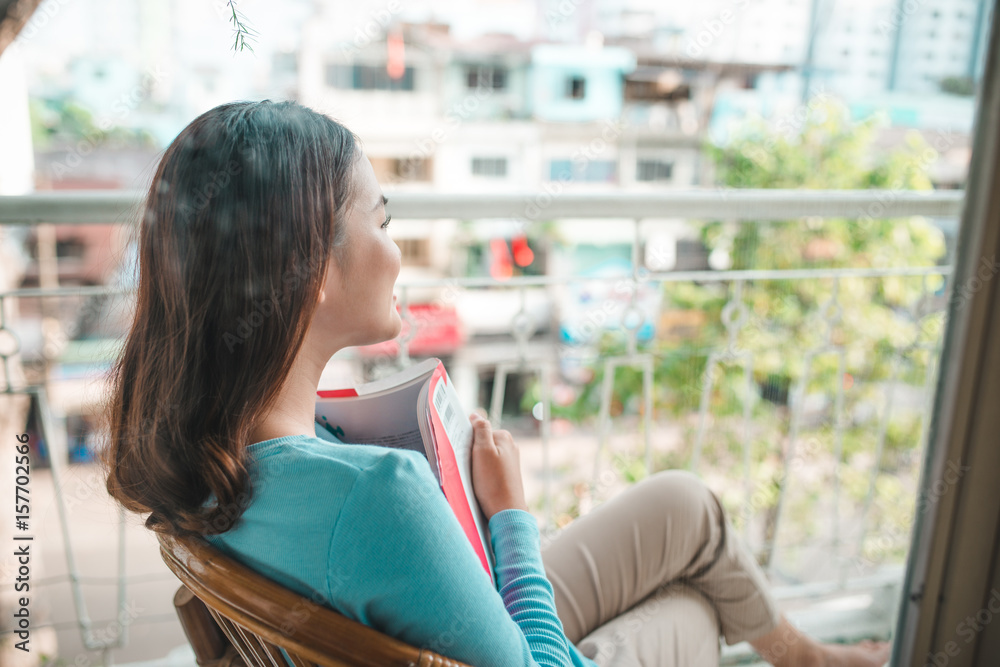 Portrait of young asian woman reading book at home