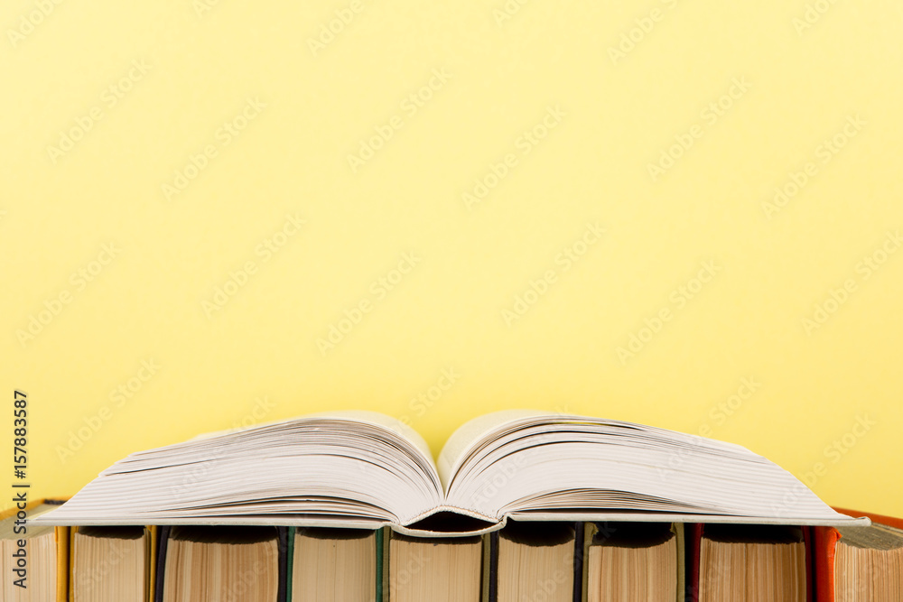 education and wisdom concept - open book on wooden table, color background