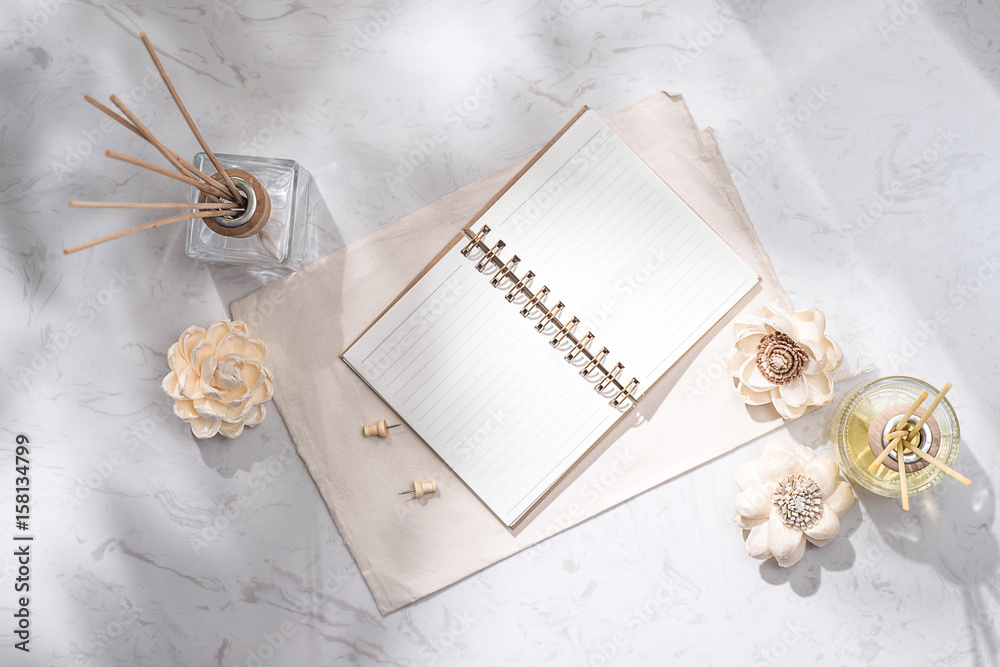 Flat lay, top view of open notebook with aroma bottle glass and wooden sticks on the table