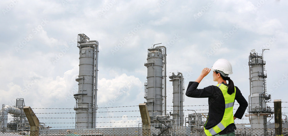 Back view of Female construction worker against gas separation plant.