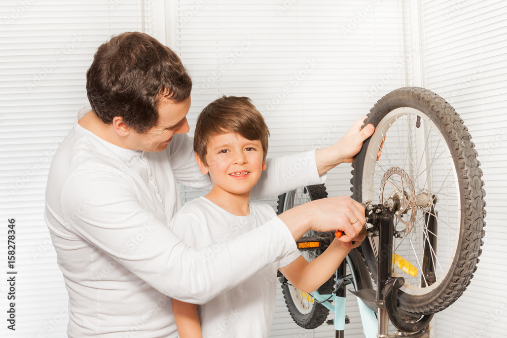 Boy helping his father repairing bicycle brakes