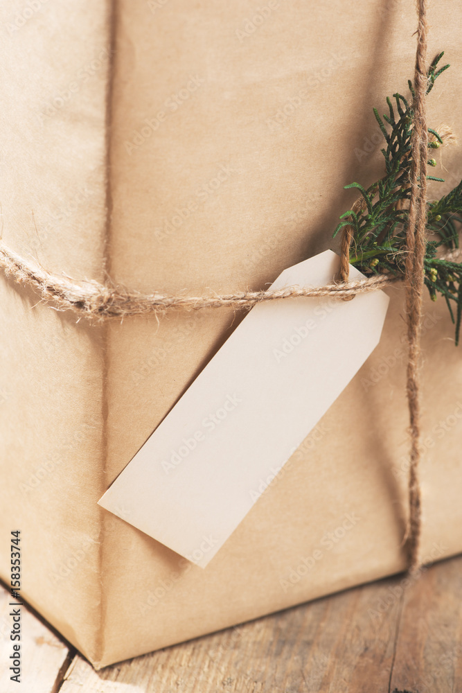 Kraft paper box and green leaves on woodean background.