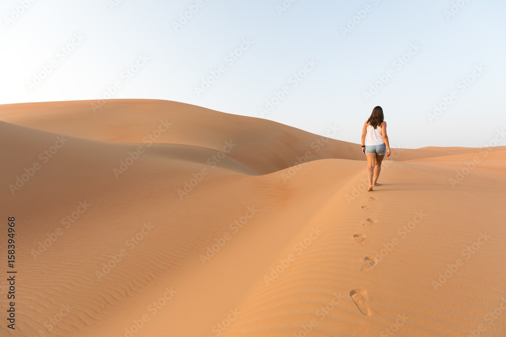 Beautiful woman hiking on giant sand dunes.