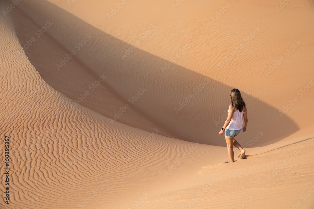 Beautiful woman hiking on giant sand dunes.