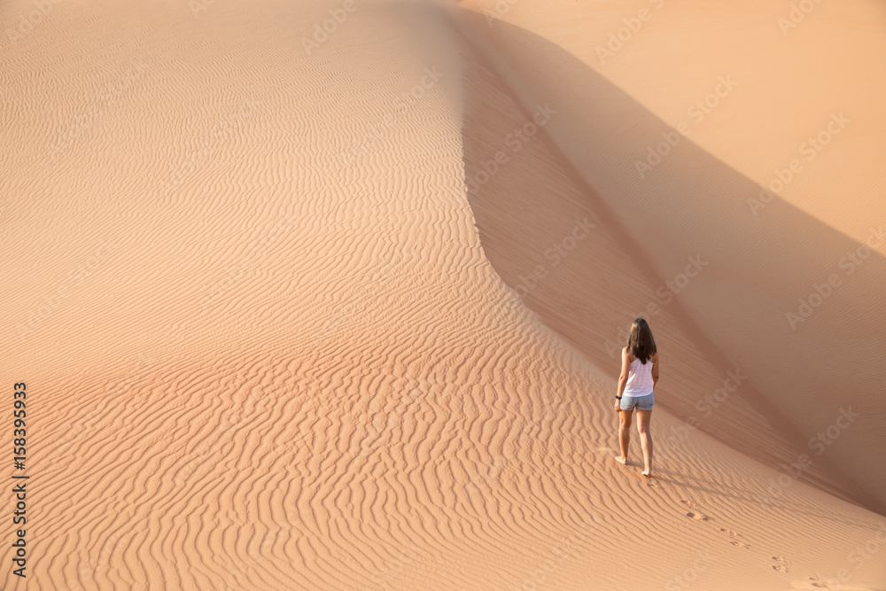 Beautiful woman hiking on giant sand dunes.