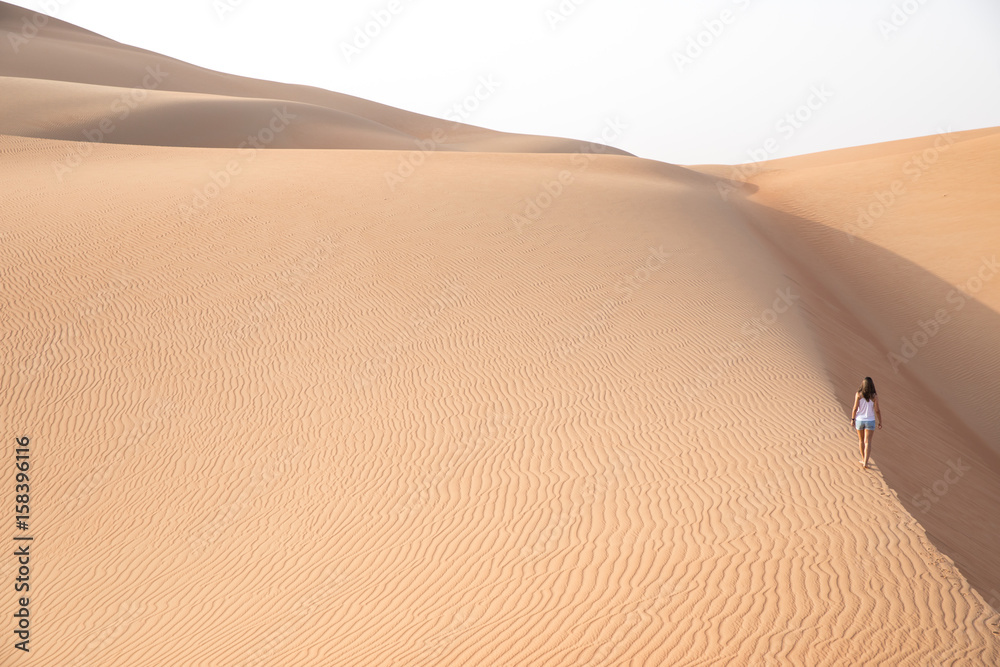 Beautiful woman hiking on giant sand dunes.