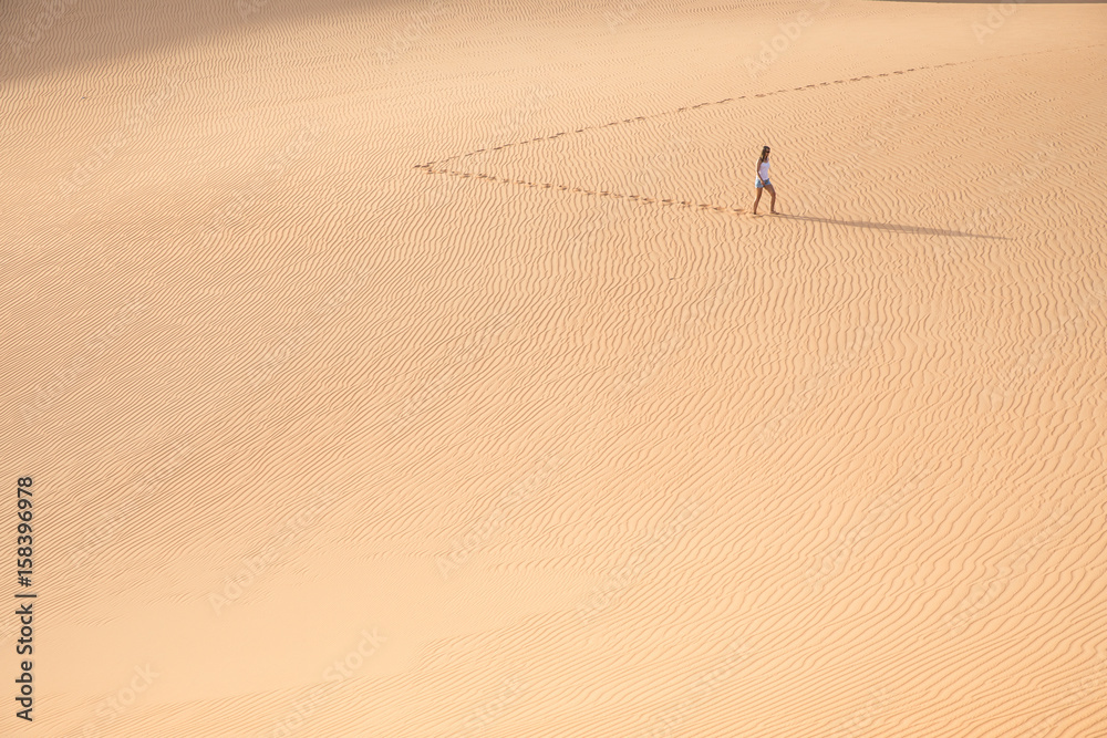 Beautiful woman hiking on giant sand dunes.