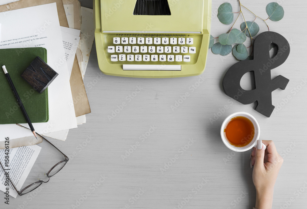 Retro Typewriter with Hand Holding Tea Cup on Gray Table