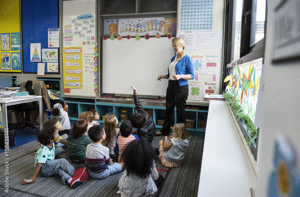 幼儿园学生坐在地板上听老师讲课