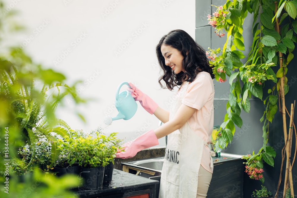 Young asian female gardener watering the plants