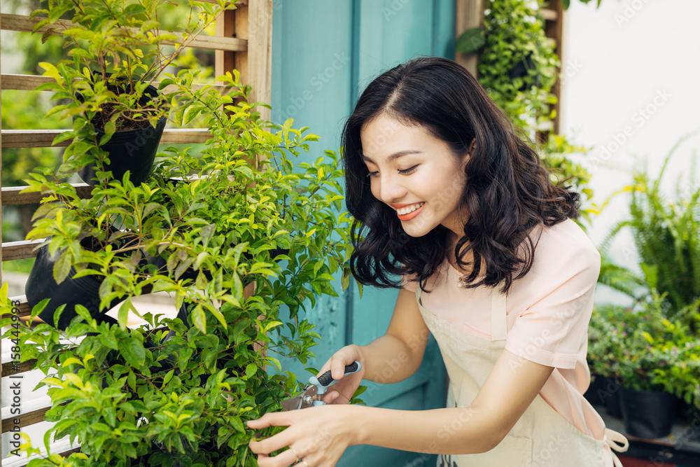 花园里穿着围裙的绿色灌木修剪器的年轻职业女性