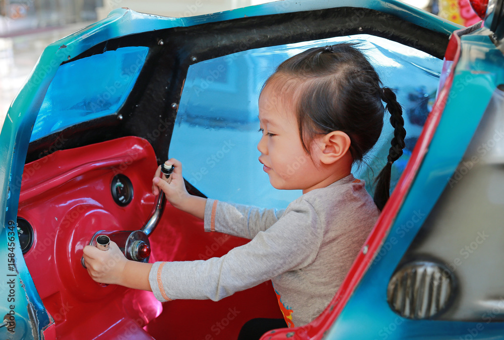 Little girl sitting and playing inside helicopter on playground.