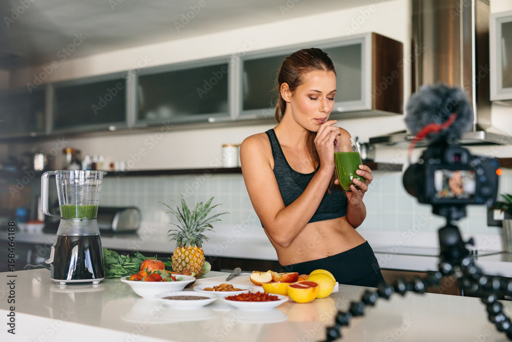 Young woman recording content for her video blog in kitchen.