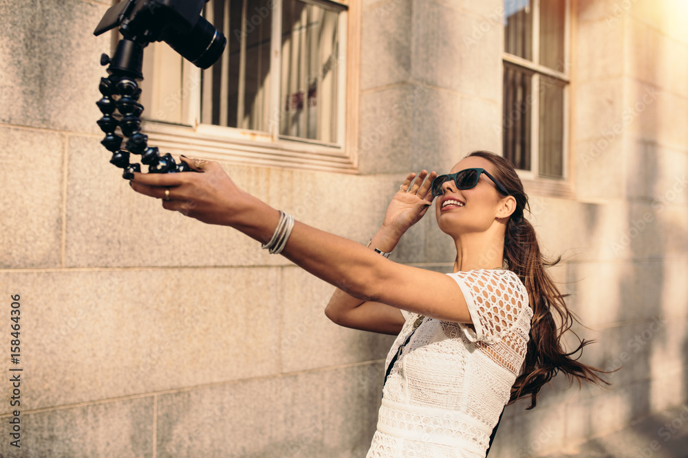 Young tourist recording selfie video while walking in the street