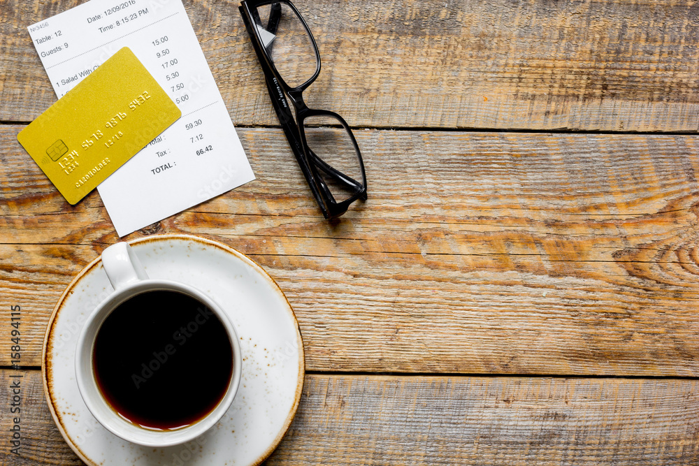 credit card for paying, coffee and check on cafe wooden desk background top view mock up