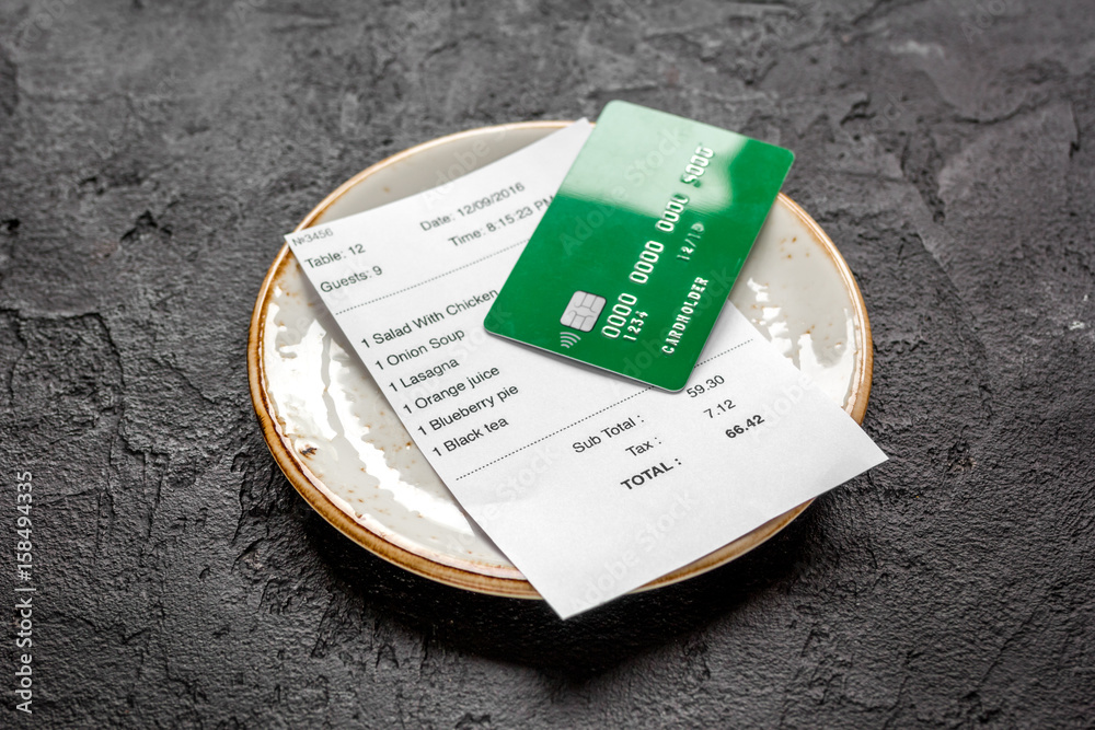 plate and receipt bill for payment by credit card dark table background