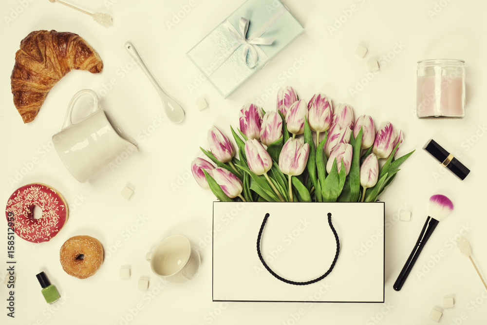 Top view of spring flowers, coffee, mobile phone, croissants, gift and cosmetics