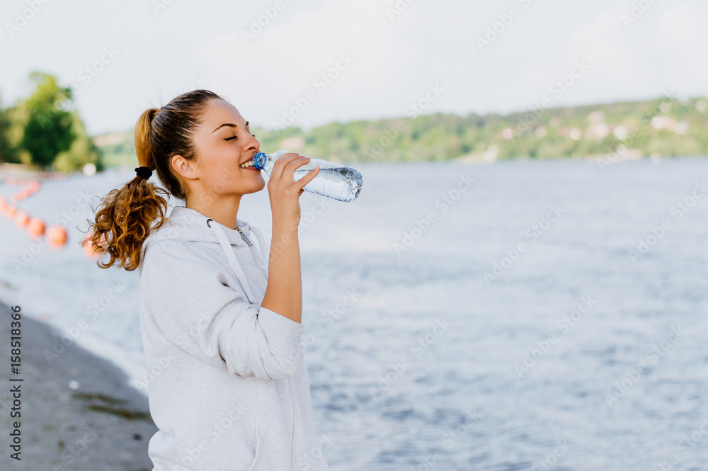 健身女孩晨跑后在河边喝水