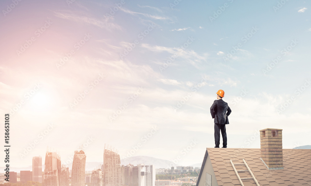 Engineer man standing on roof and looking away. Mixed media