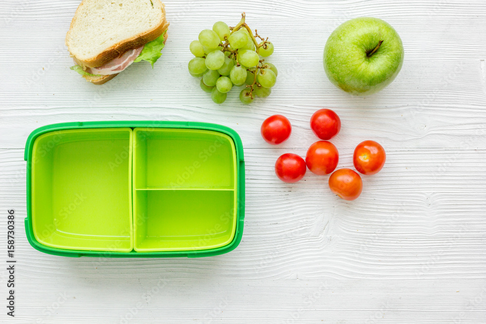 school lunch set with apple and vegetables in lunchbox background top view