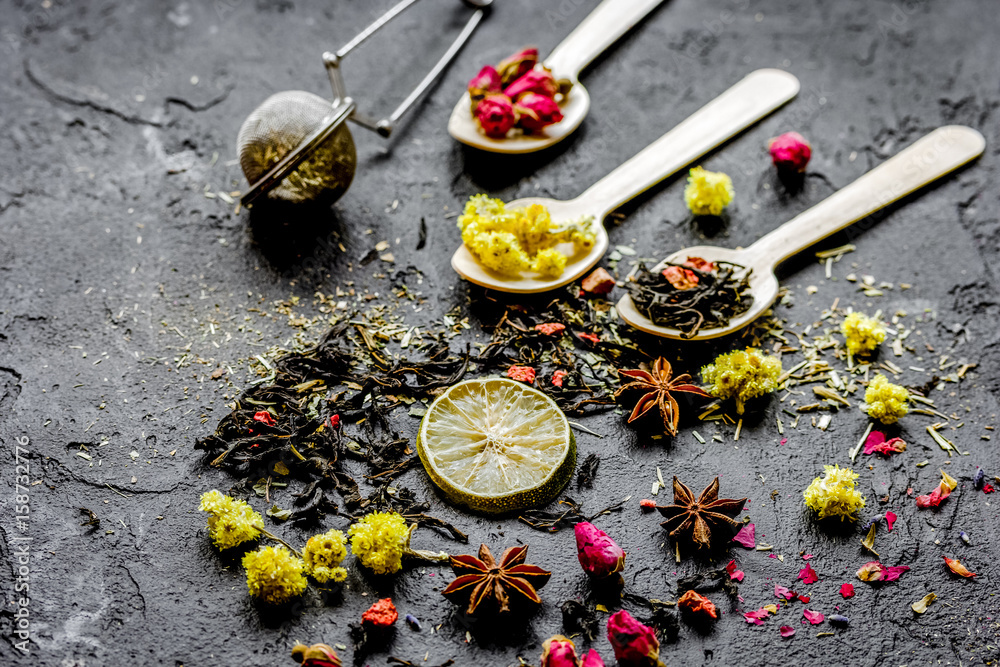 Spoons with herbs on dark stone background