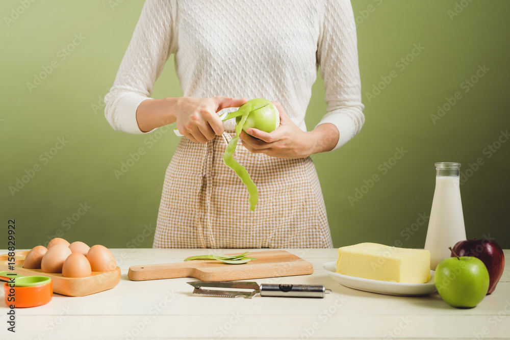 穿着围裙的家庭主妇制作。烹饪苹果蛋糕的步骤。切青苹果。