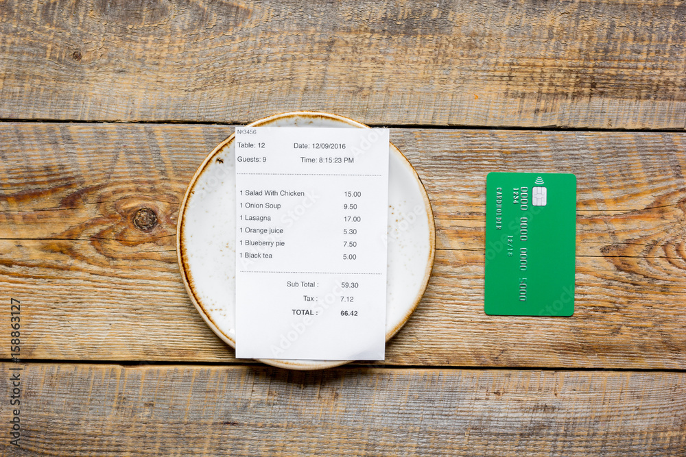 paying check for lunch with card wooden table background top view