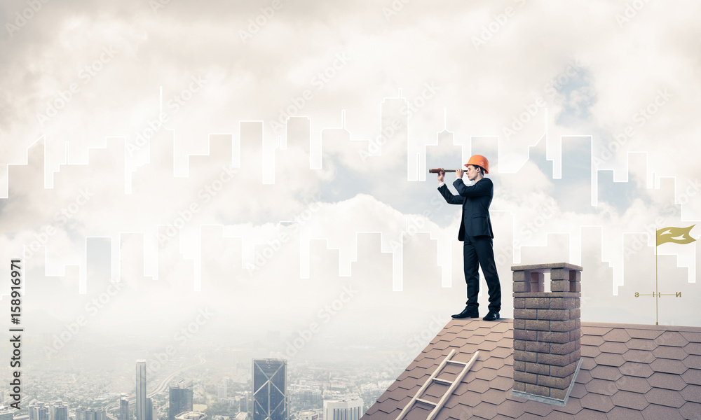 Engineer man standing on roof and looking in spyglass. Mixed med