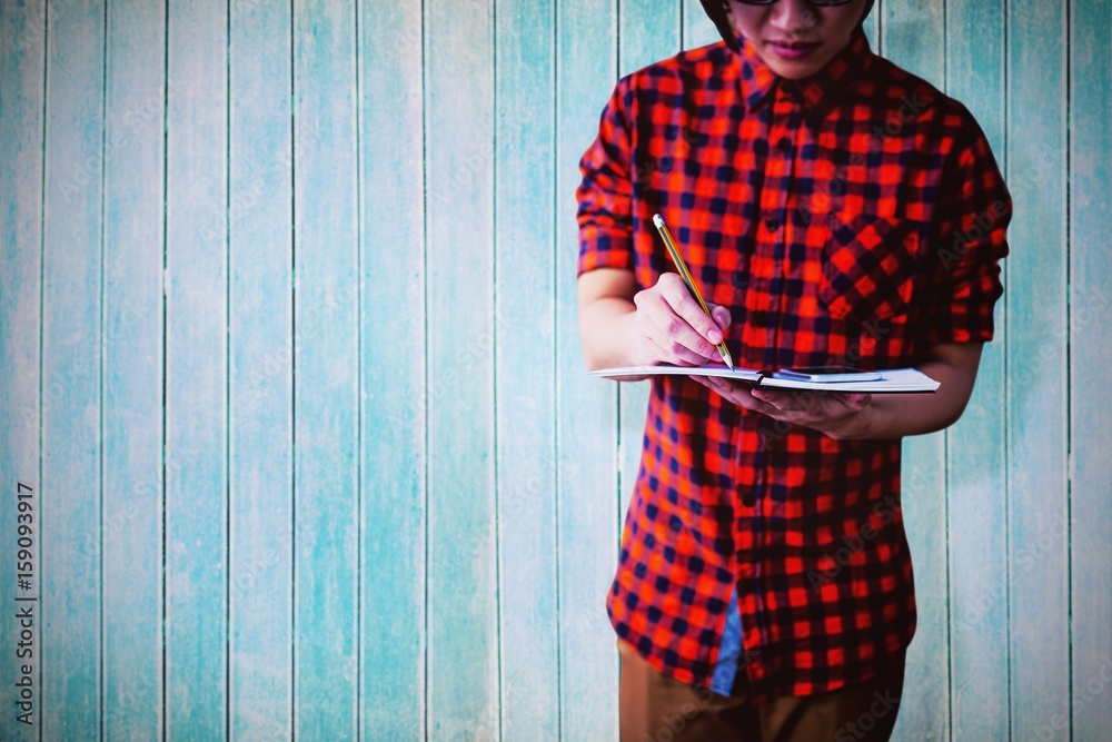 Composite image of mid section of young man writing on notebook 