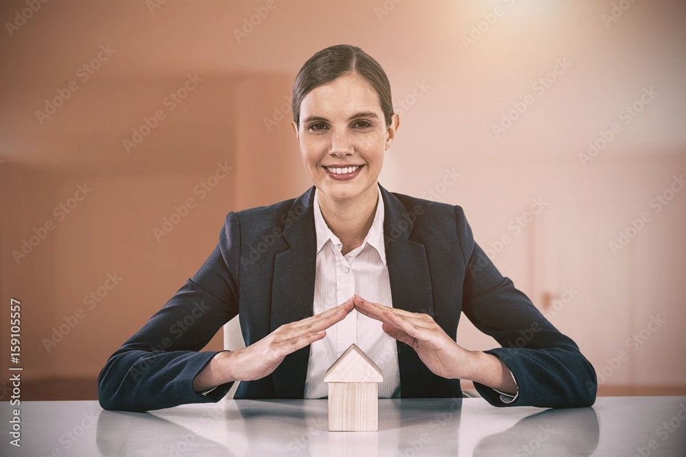 Composite image of insurer protecting a house by his hands