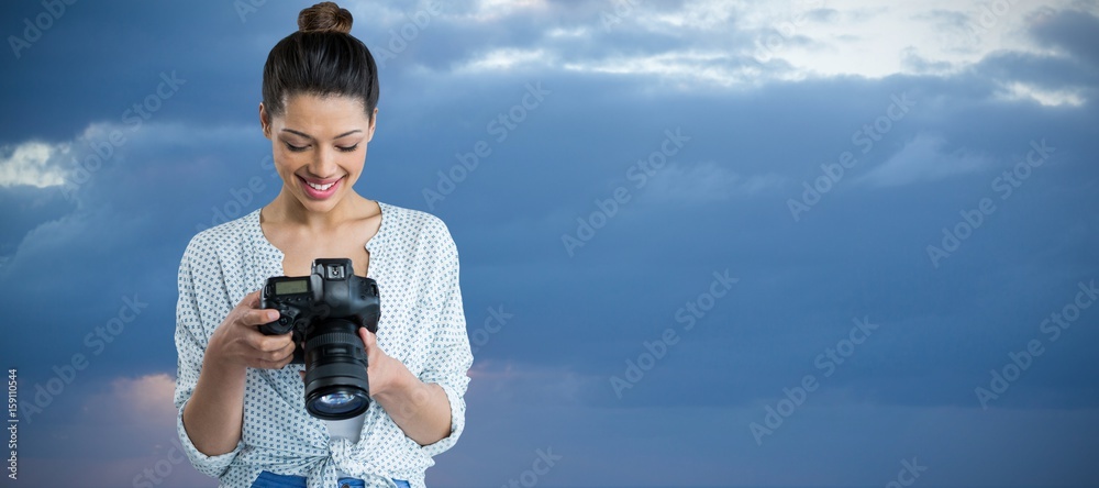 Composite image of smiling young woman holding digital camera 